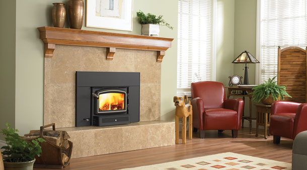 Living room view with fire lit in a tiled fireplace with a wood mantle, red chairs and a dog statue