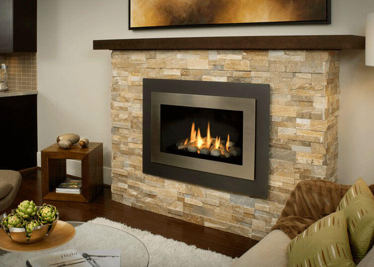 Valor H4 Gas Fireplace with beige stone surround and wood mantle in a living room with cozy ambiance