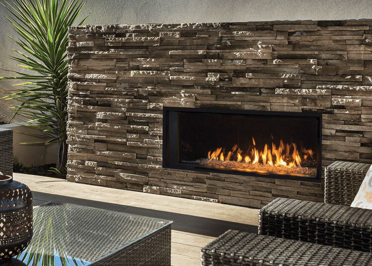 Valor L1 Linear Gas Fireplace with layered stone surround and two chairs and table in the foreground