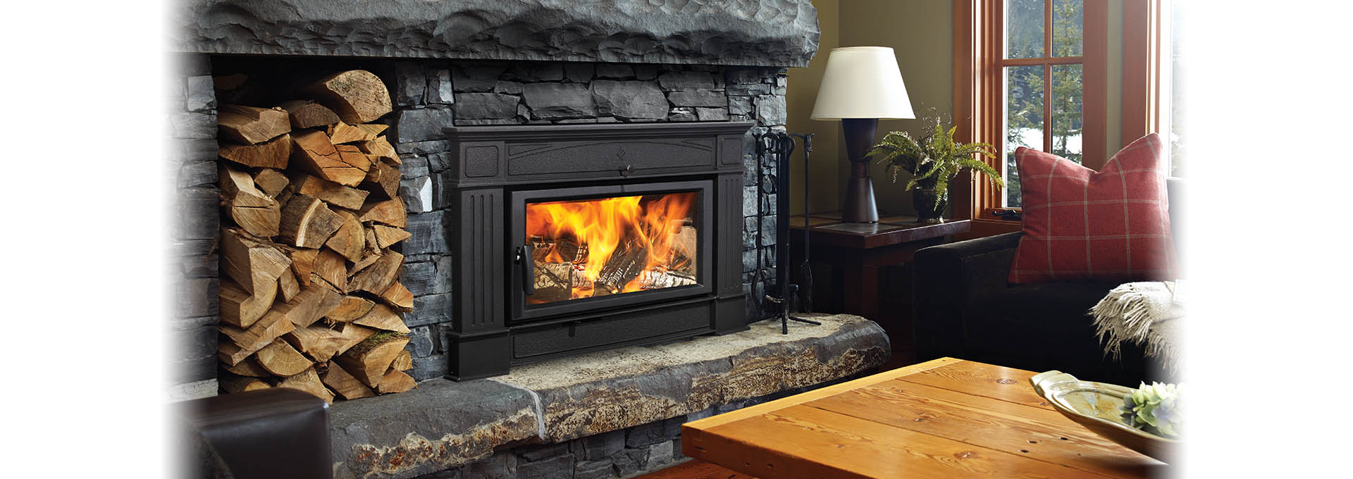 Hampton Hi500 Wood Insert with dark natural cut stone surround and wood pile stacked next to it