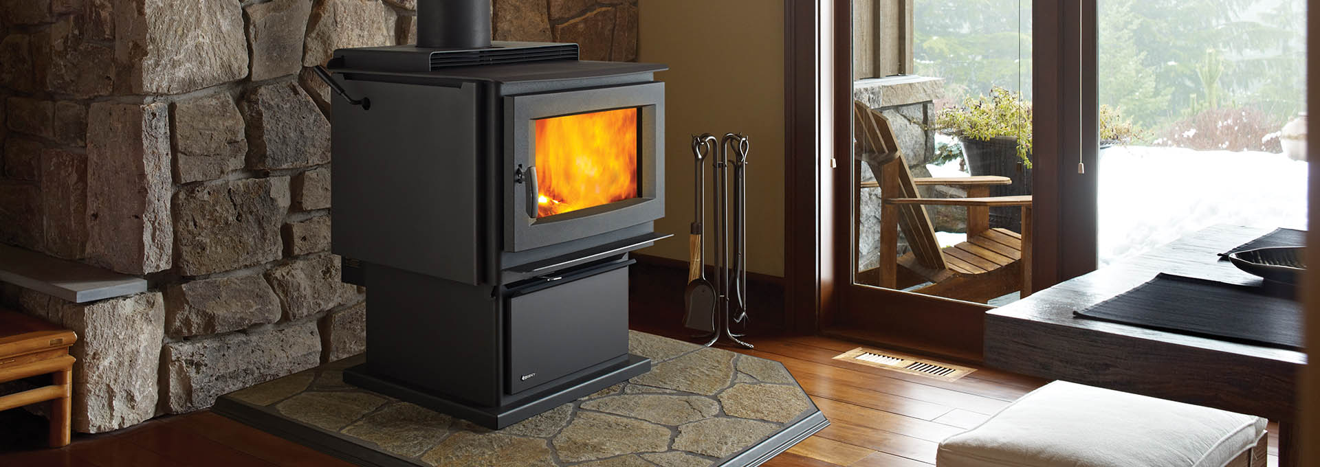 Regency F5200 Wood Stove in front of stone mantle and deck view out window next to it