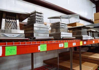 Variety of stainless steel chimney caps on shelf in warehouse