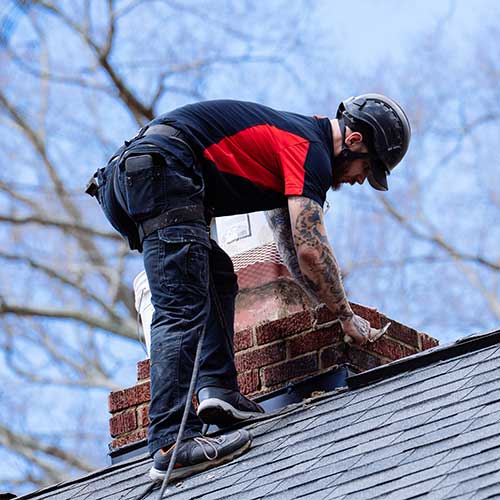 Chimney Technician Completing Repairs to Brick Chimney on Roof