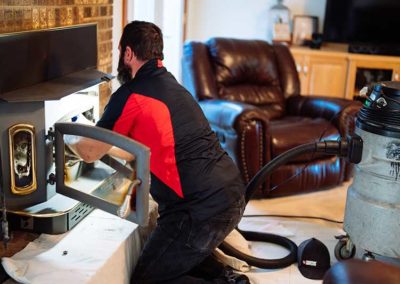 Technician performing chimney sweep service in firebox