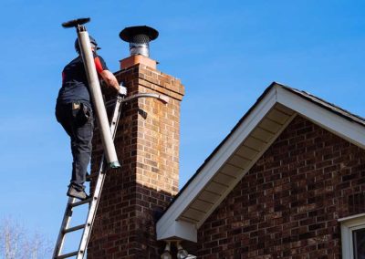Technician climbing ladder to chimney with sweep tools to complete service