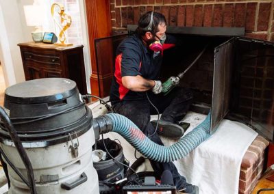 Technician using chimney vacuum in firebox