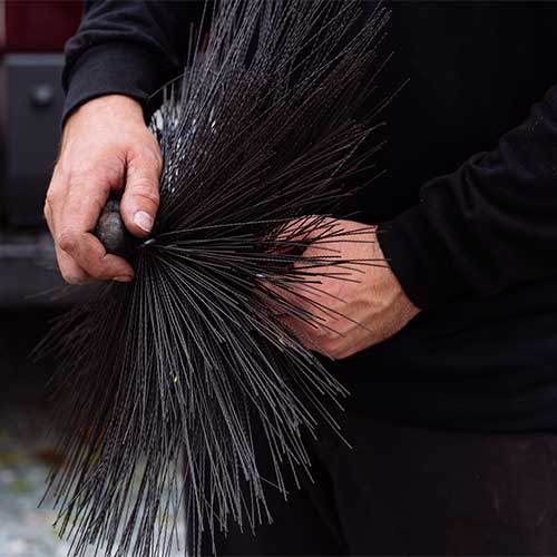 Close up of chimney sweep's hands holding chimney sweep broom 