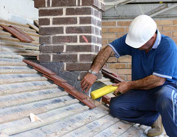 Chimney technician repairing chimney flashing on roof