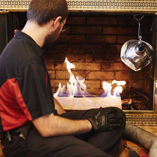 Technician Sitting on Hearth Servicing a Gas Fireplace