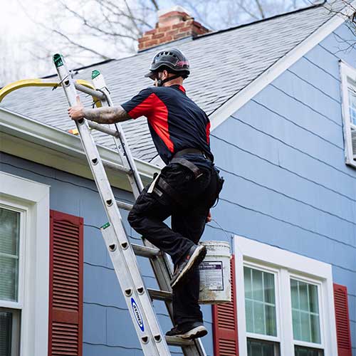 Chimney technician climbing ladder to roof to repair chimney leak