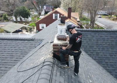 Technician restoring brick and mortar around chimney crown
