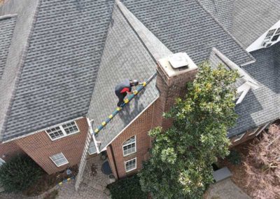 Aerial view of technician climbing roof for chimney restoration