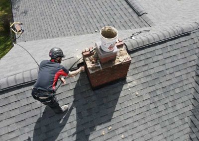 Aerial view of technician repairing masonry and mortar on chimney crown