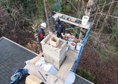 Aerial view of two technicians rebuilding chimney and crown