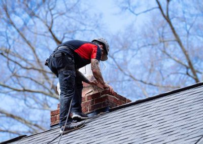 Technician on roof repairing brick and mortar around chimney