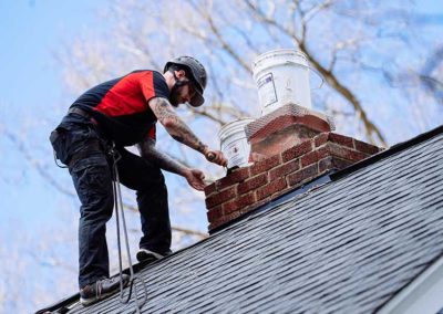 Technician standing on roof laying mortar on chimney