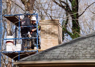 Technicians on roof repairing chimney crown