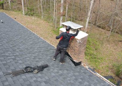 Technician on roof installing new stainless chimney cap