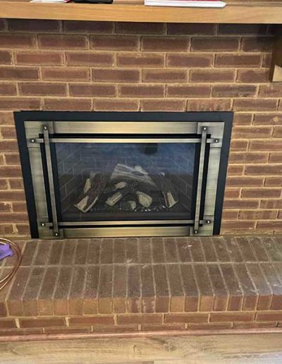 Brick fireplace with wood mantle and new gold frame with glass after chimney repair
