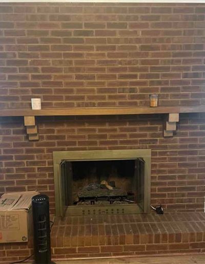 Brick fireplace with wood mantle and gold frame before chimney repair