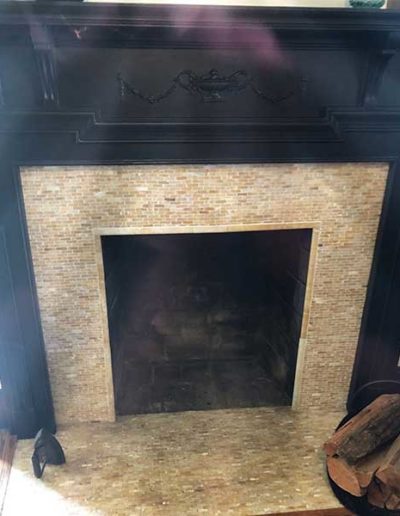 Beige tiled fireplace with black mantle and no frame before repairs