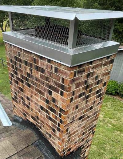 Clean and repaired chimney on roof with new, larger chimney cap with screen after repairs