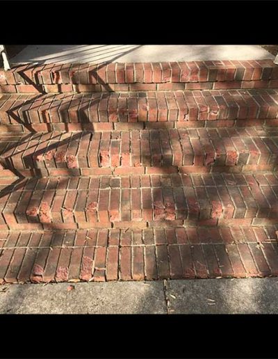 Brick residential front steps with cracks and missing mortar before repairs