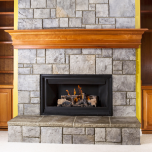 gas fireplace with gray bricks and a wood mantel