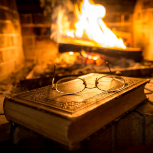 a gold-covered book with glasses on top of them in front of a burning fire