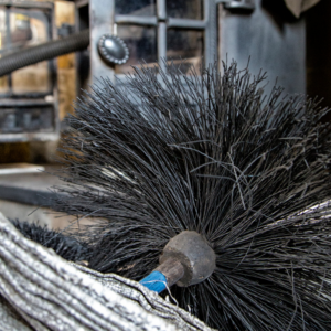 a wire chimney cleaning brush with a cast iron stove in the background