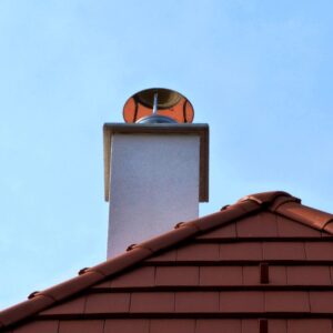 a white chimney with a metal chimney cap