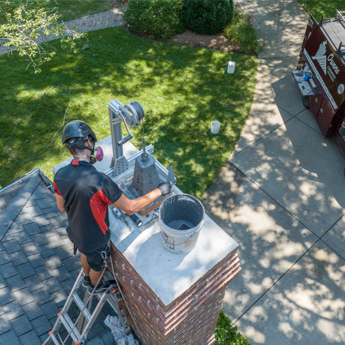 Technician Completing Brick Chimney Restoration on Roof