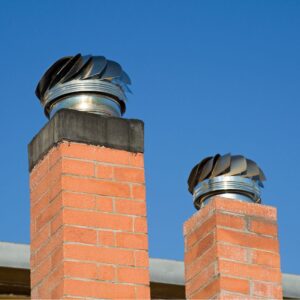 two masonry chimneys with metal chase covers and specialty caps