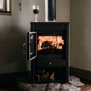 a black wood stove with a fire going and a glass of wine sitting on top of it