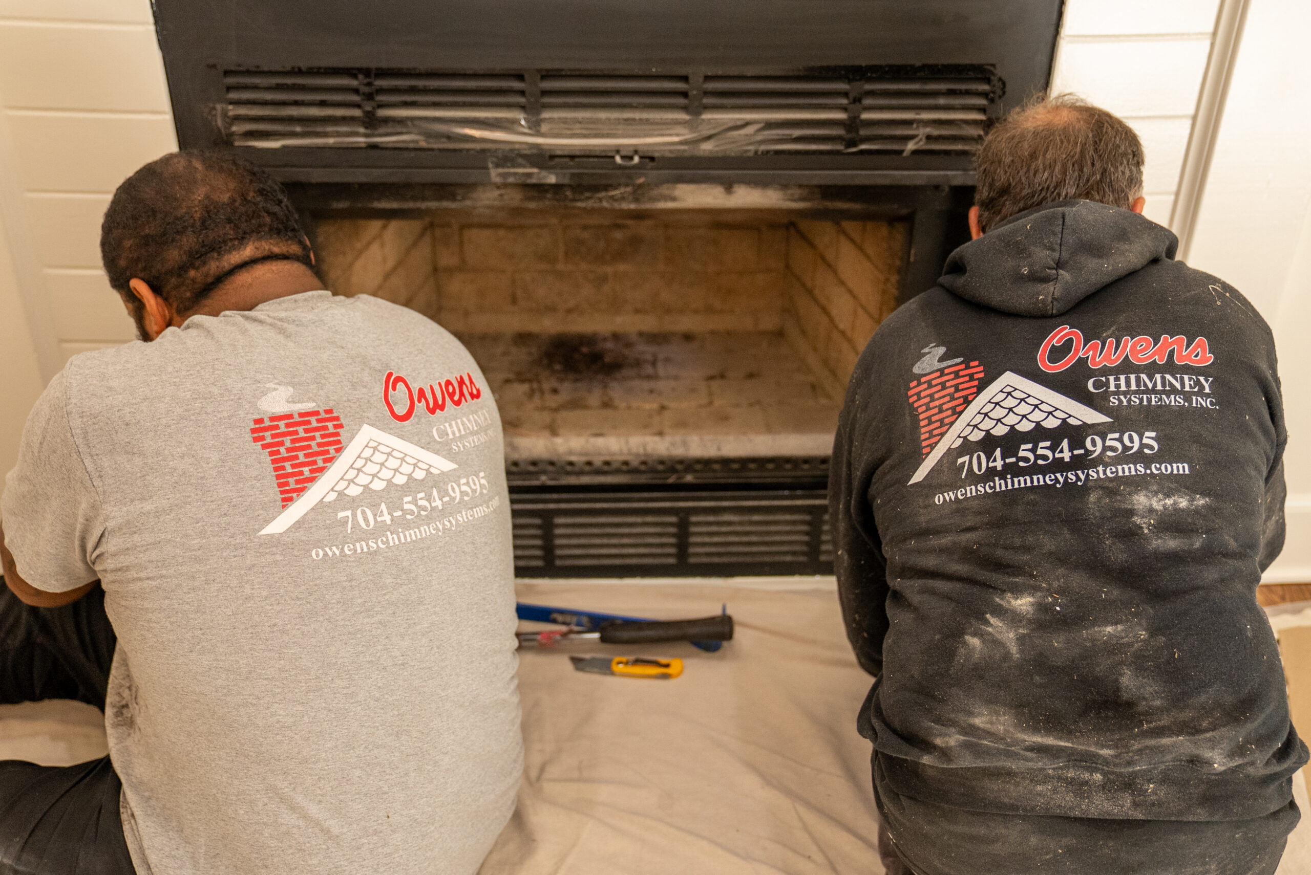 Owens Chimney Systems techs work on a fireplace.